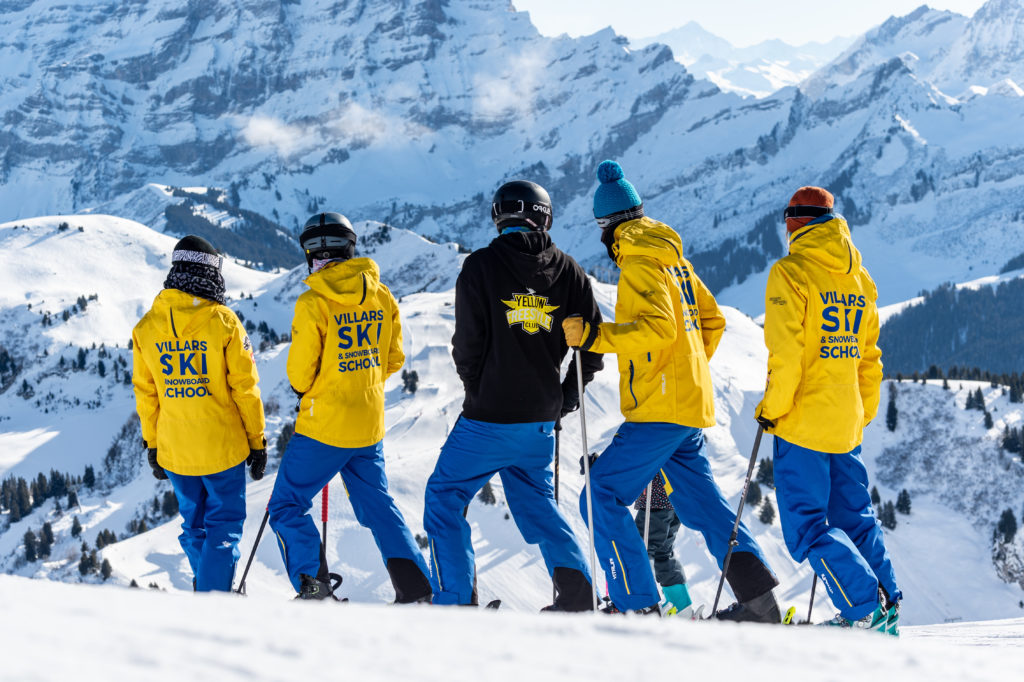 moniteurs de ski de la Villars ski school en jaune et bleu devant de magnifiques montagnes enneigées