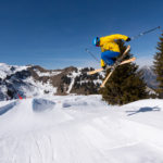 notre moniteur jaune et bleu qui saute sur une table au snowpark et fait un grab en ski