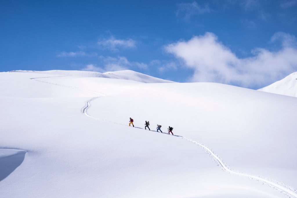 un groupe de 4 personnes qui font du ski de randonnée / peaux de phoque en montagne